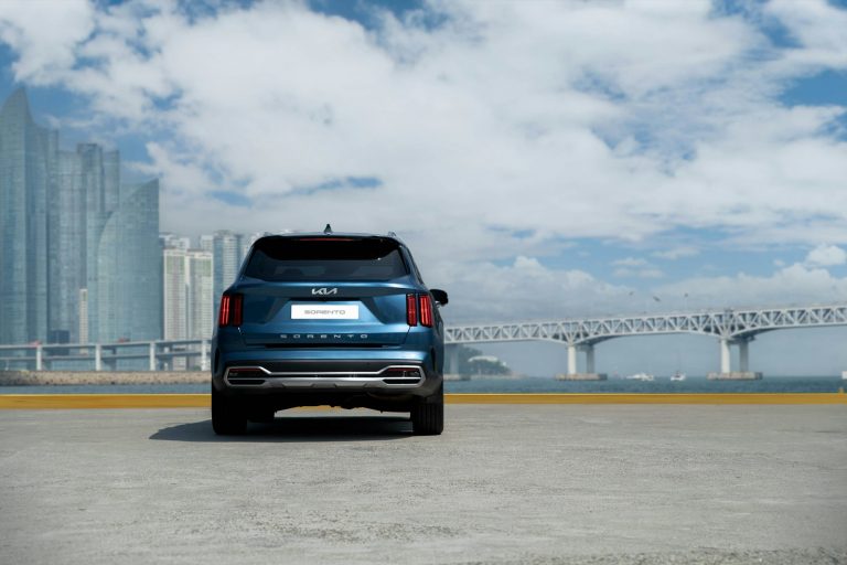 a blue car parked in front of a bridge