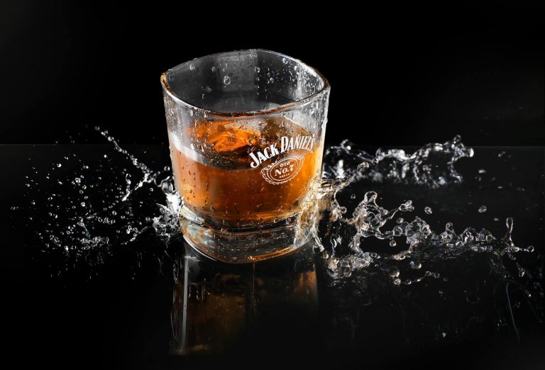 Dynamic shot of whiskey with ice and splash, highlighting Jack Daniel's brand on glass.